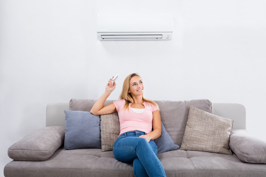 Woman Operating Air Conditioner With Remote Control Carrier Named Best HVAC Company of 2022 by U.S. News & World Report